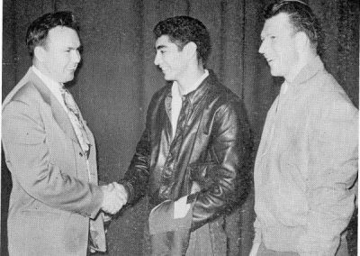 Another memorable student assembly (one was held each week) that same year, the jersey numbers of Gene LaShell (left) and Frank “Keko” Munoz (right), both veterans, were retired for twenty years. LaShell, jersey number 54, who had lost both legs in service, was honored for his great halfback moves in 1941. Munoz, jersey number 14, who was 5 feet, 7 inches tall and weighed only 150 pounds, had received serious war injuries as a paratrooper, but had come back to earn the title of Southern Junior College Player of the Year for his brilliant football playing in 1947. Munoz, who also excelled at baseball and basketball, later joined the UCLA Bruins football team. Coach Ed Goddard, who coached both greats in their playing days, is on the far right.